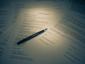 Two people signing a loan contract with pens on a wooden desk