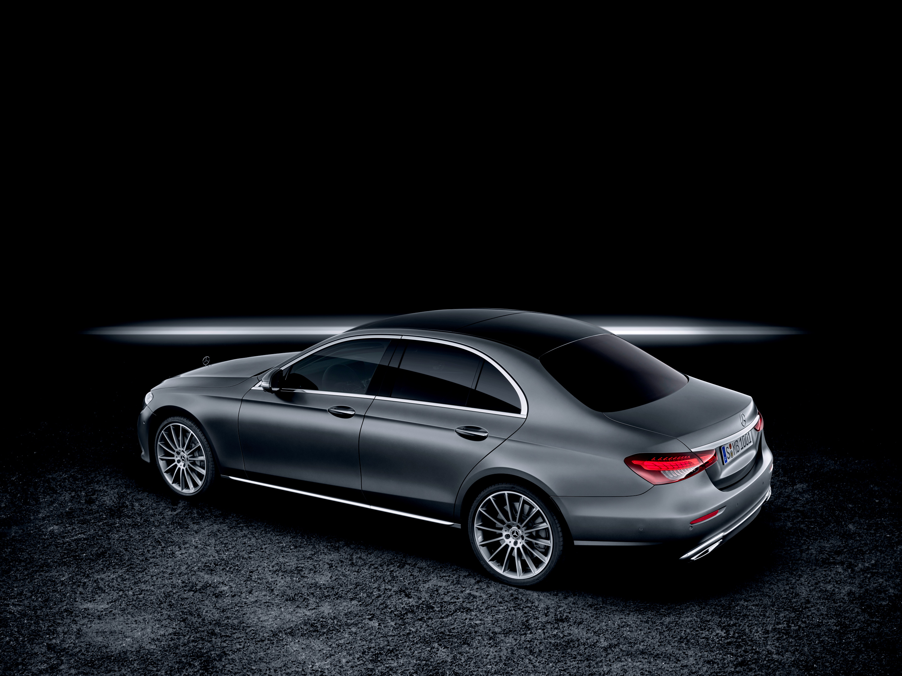 Mercedes E-Class W213 saloon rear three-quarter view, full-width tail-light treatment and AMG Line bumper