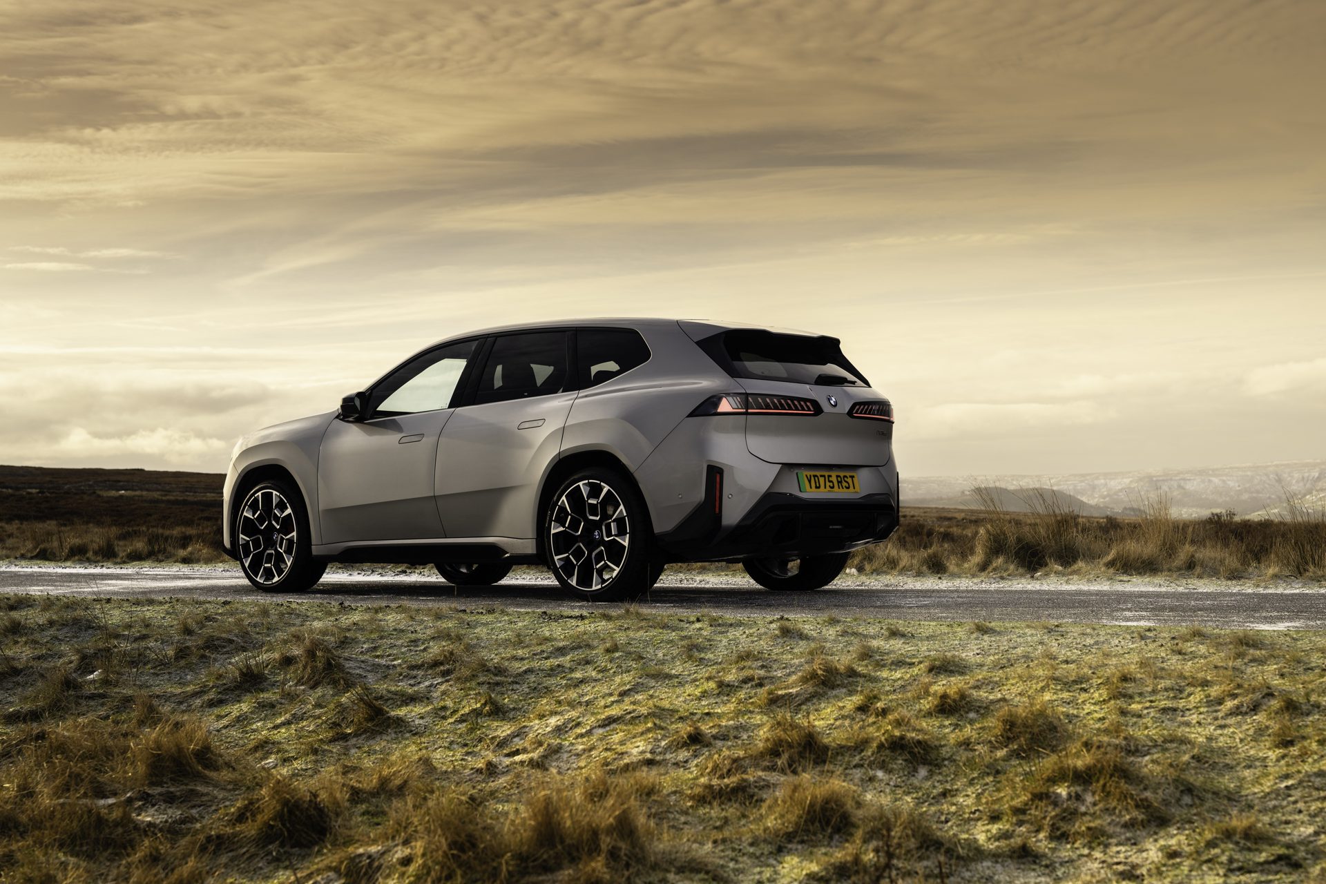 BMW iX3 electric SUV parked at dusk on a moorland road, rear three-quarter view, UK registration
