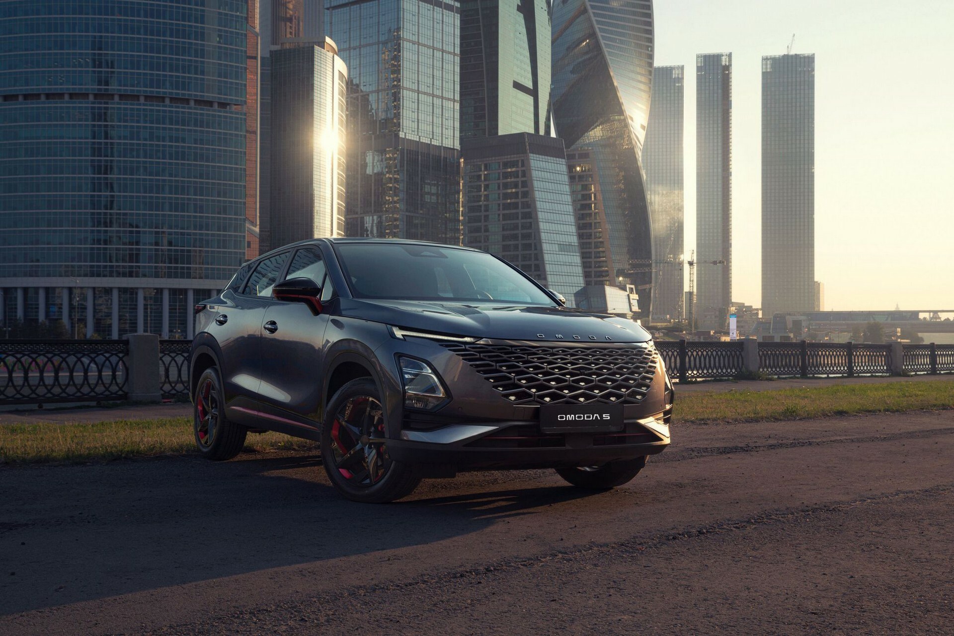 Omoda 5 PCP family SUV photographed against a city skyline at golden hour