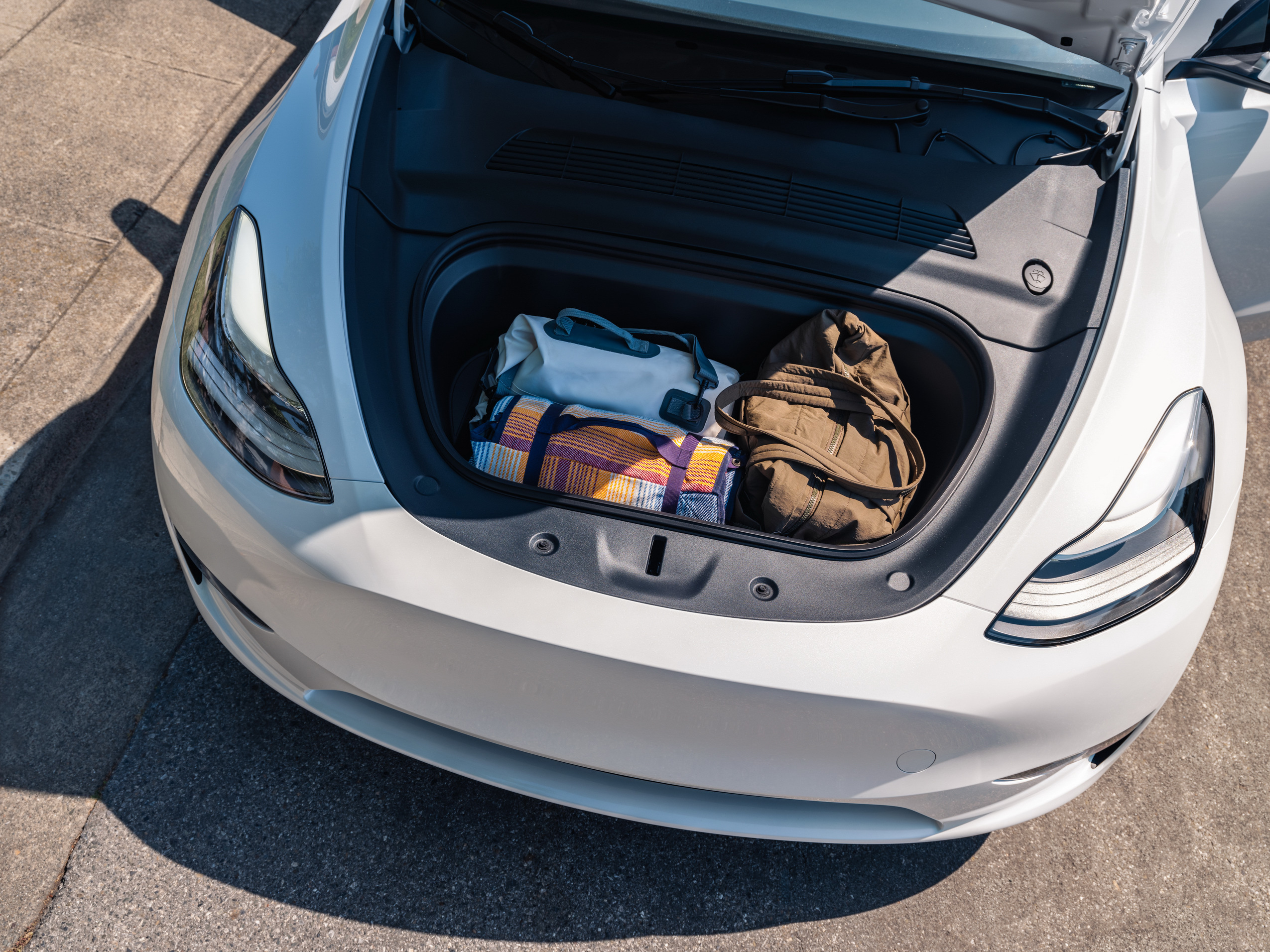 Used Tesla Model Y front boot or frunk loaded with luggage, showing practicality