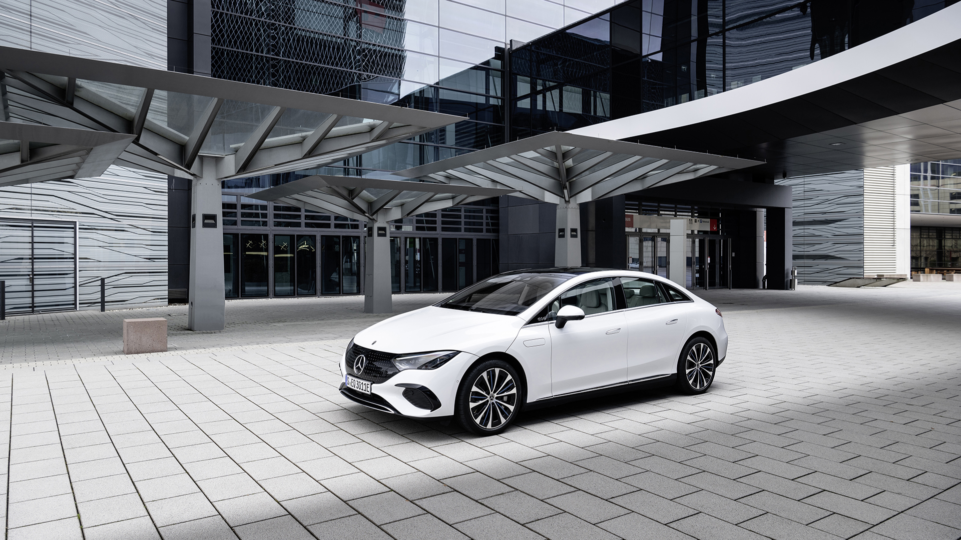 Mercedes EQE 300 saloon front three-quarter view outside a glass building