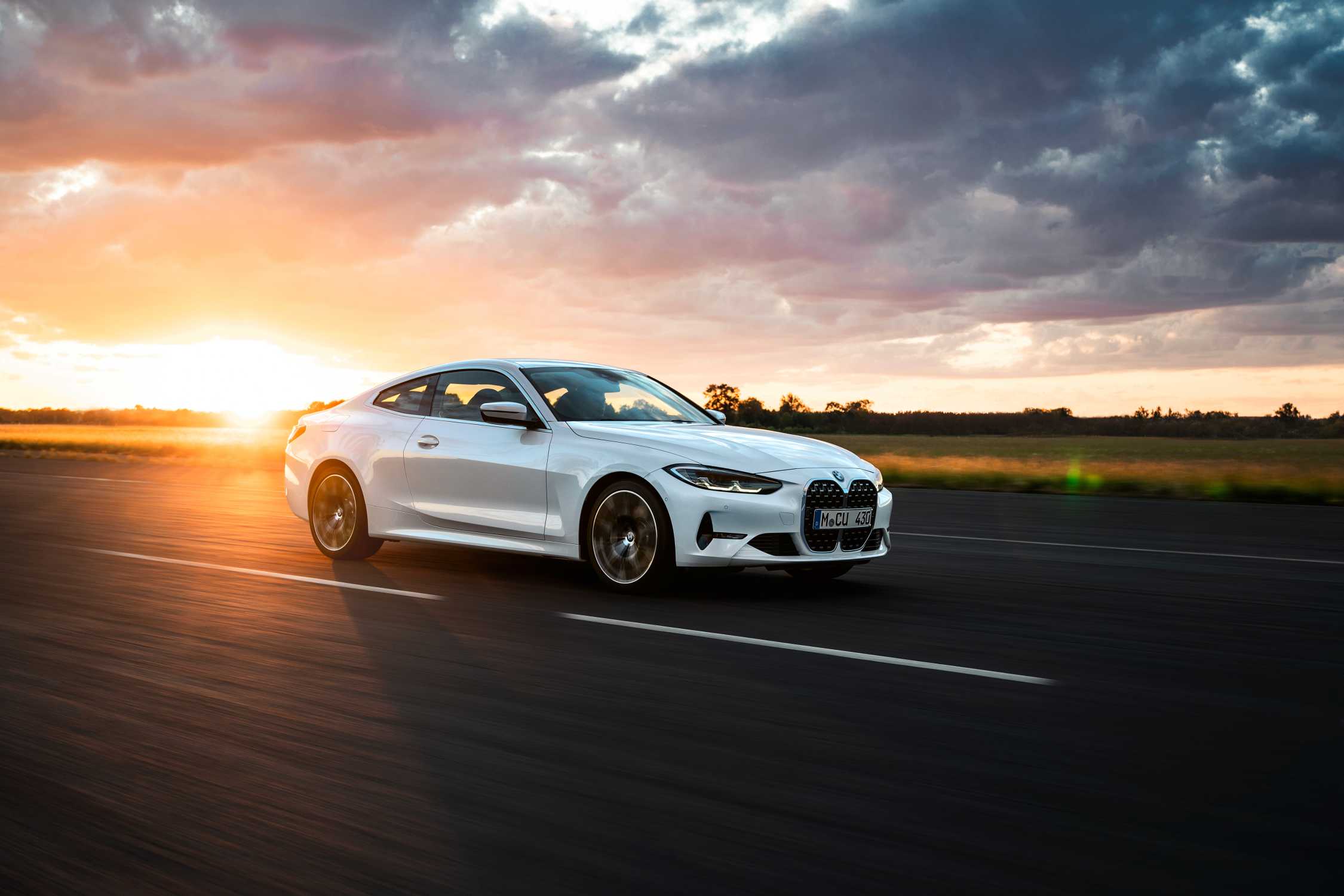 BMW 4 Series G22 used 430i coupe in white driving into a sunset