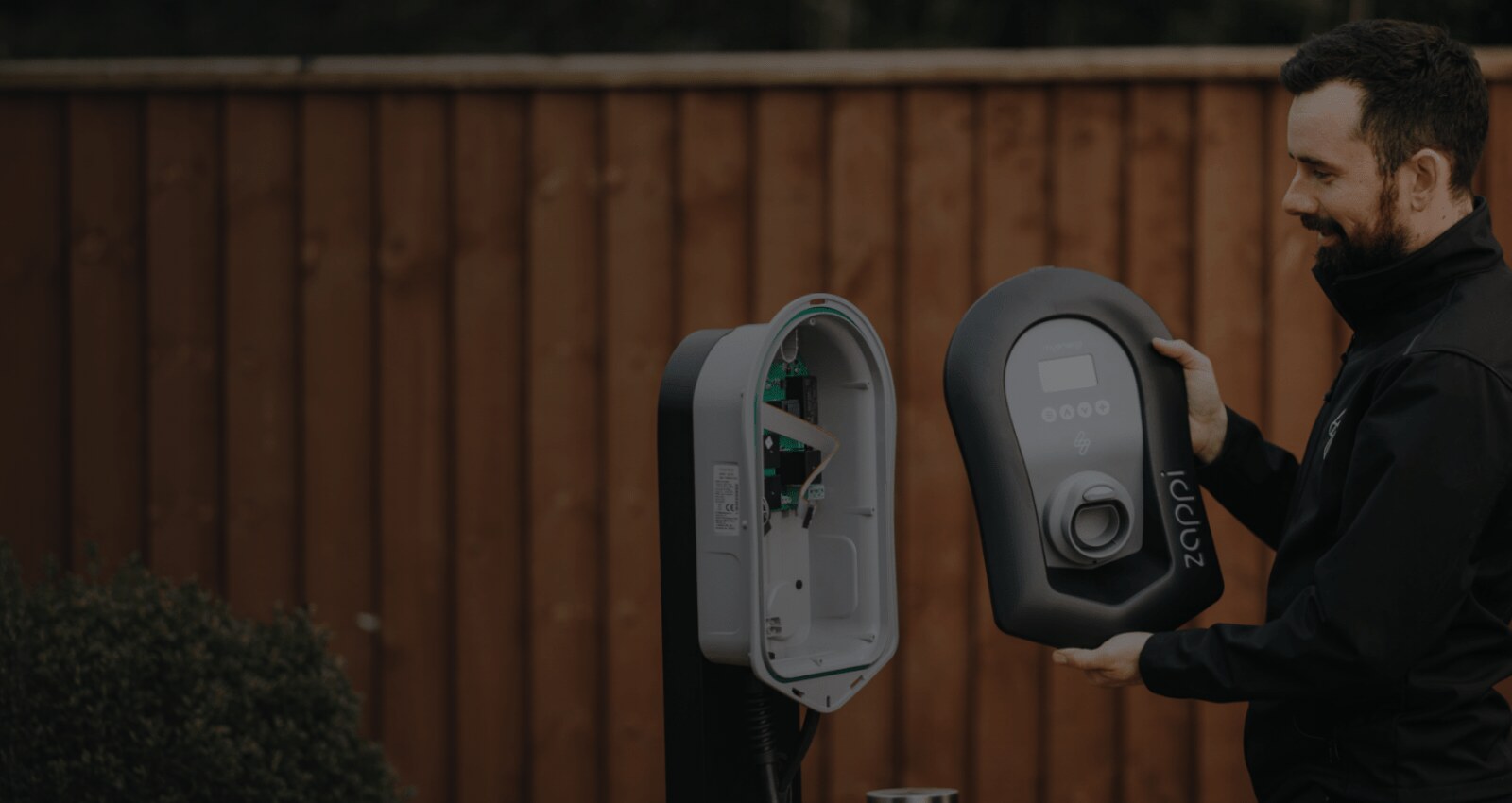 Zappi home EV charger being fitted to a garden wall by an installer