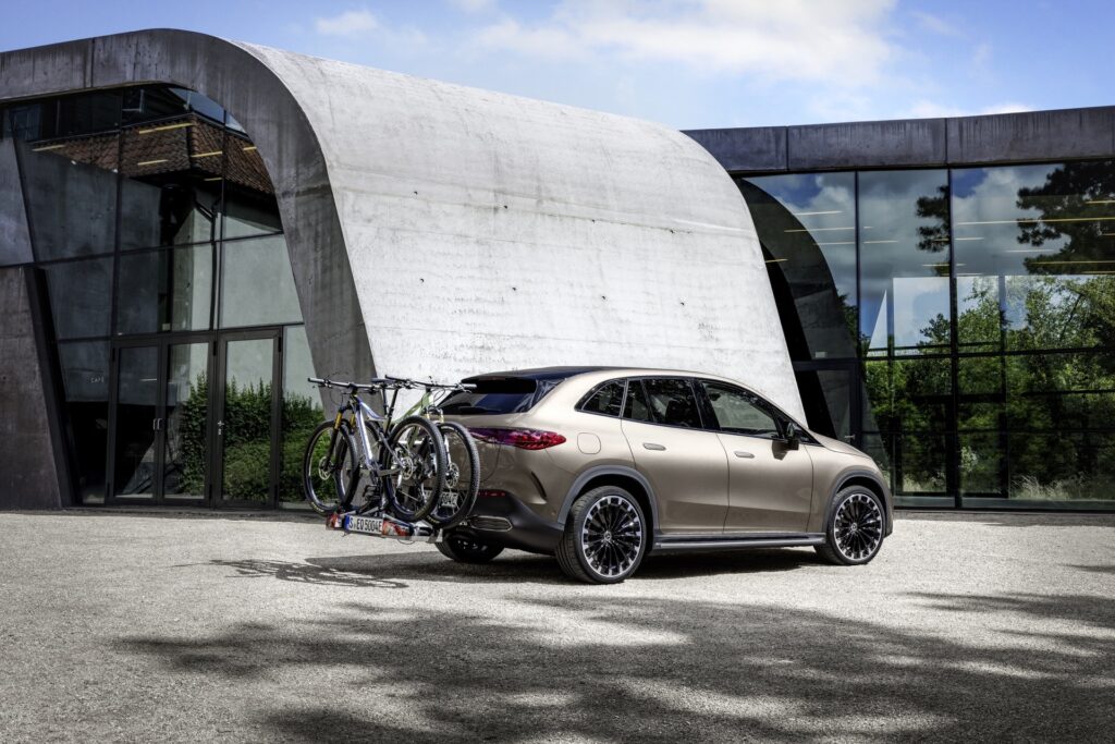 Mercedes EQE SUV with bikes loaded on a rear rack outside a modern building