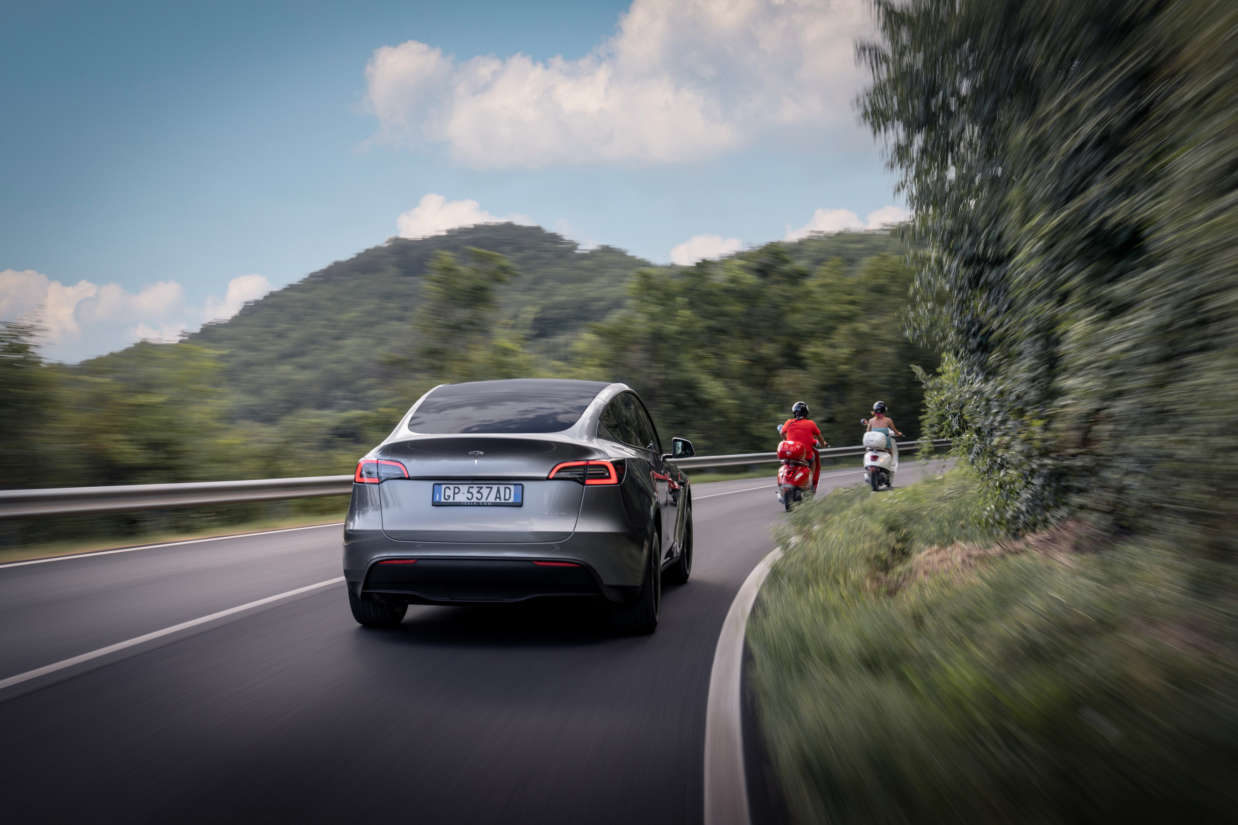 Used Tesla Model Y rear view in grey on a winding mountain road