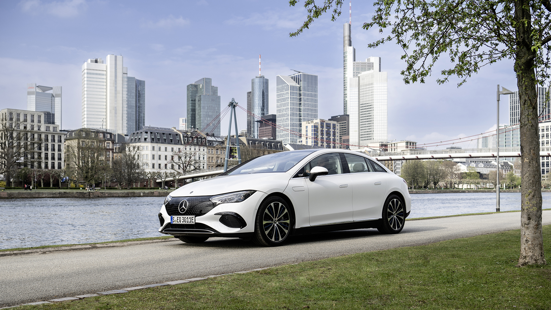 Mercedes EQE saloon in white parked by a city riverside, the executive EV at the centre of salary sacrifice maths