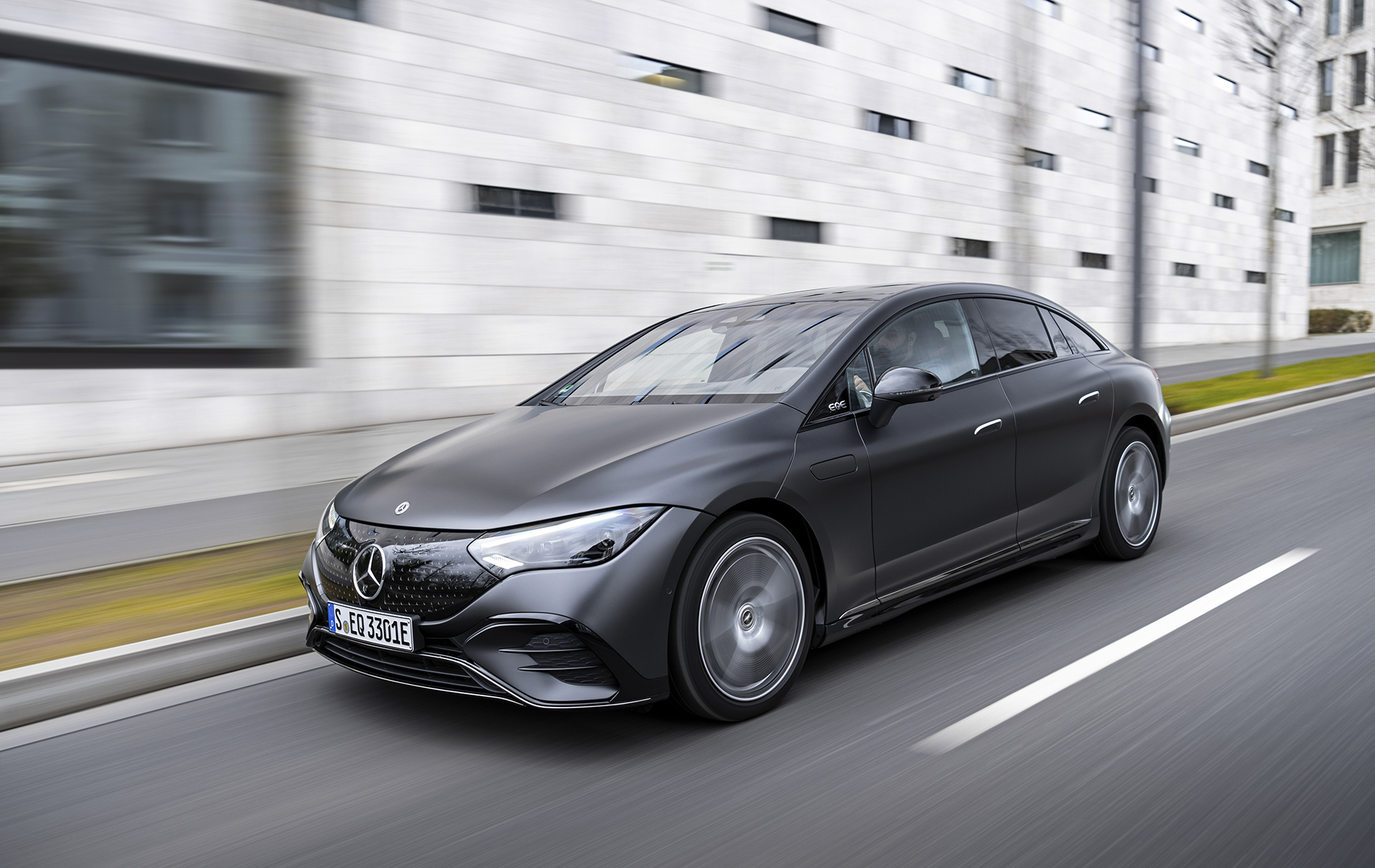 Grey Mercedes EQE saloon driving on a city road, the long-range executive EV