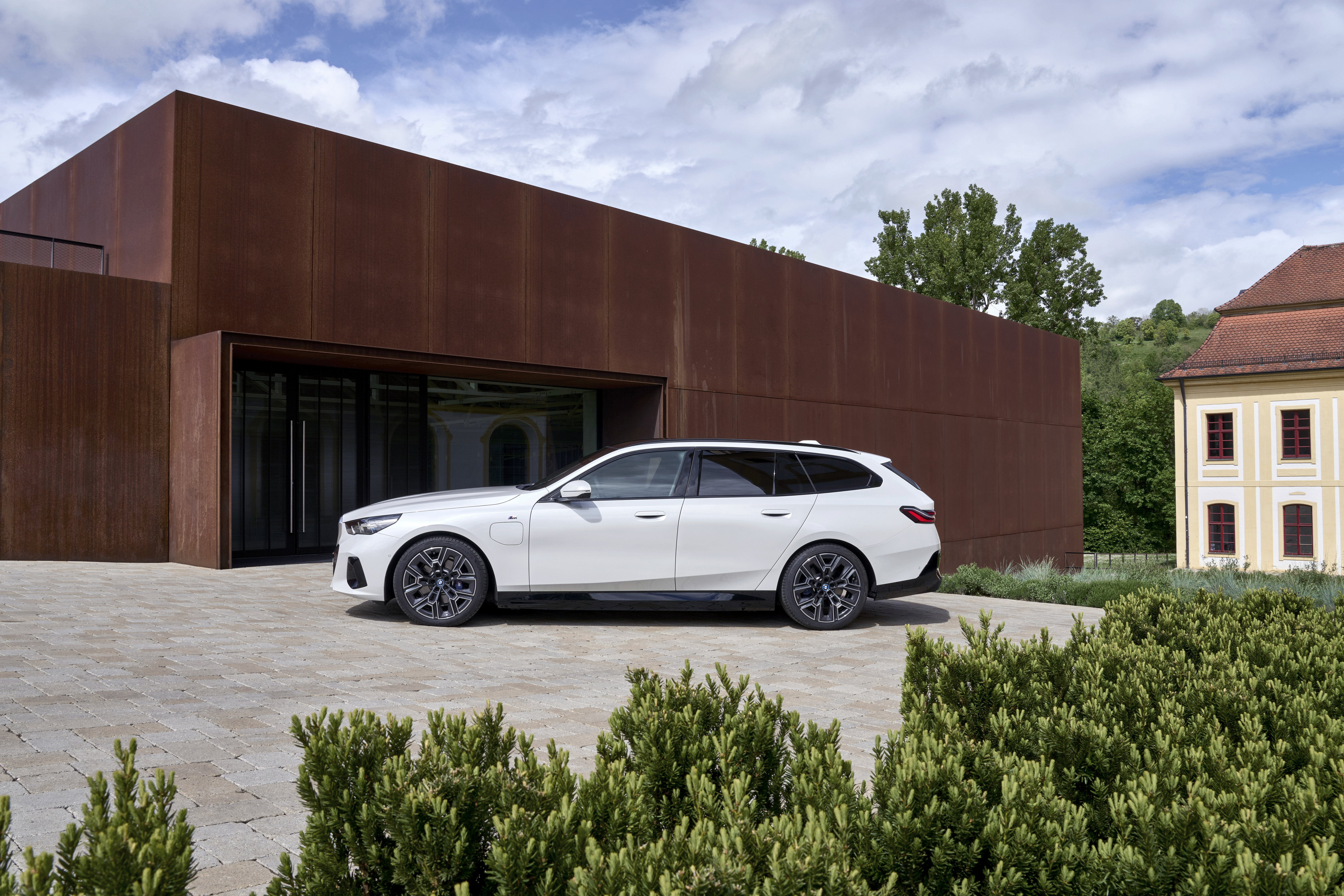 BMW 5 Series G61 Touring 530e by a modernist building, monthly PCP round