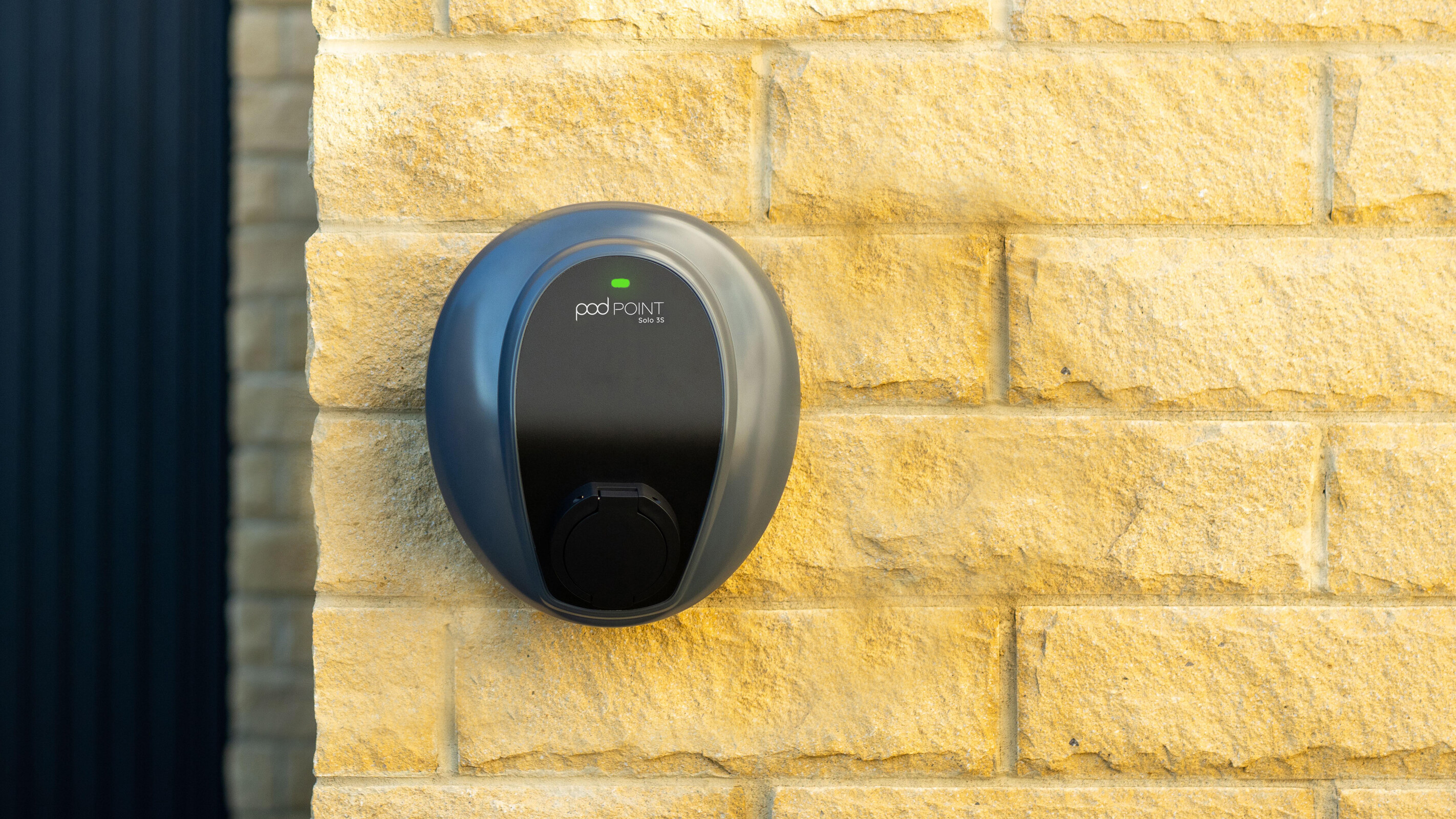 Pod Point Solo home EV charger mounted on a brick house wall