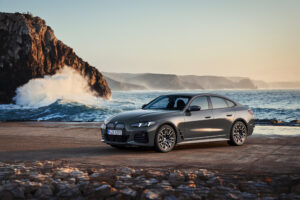BMW i4 electric Gran Coupe parked by the coast, front three-quarter view