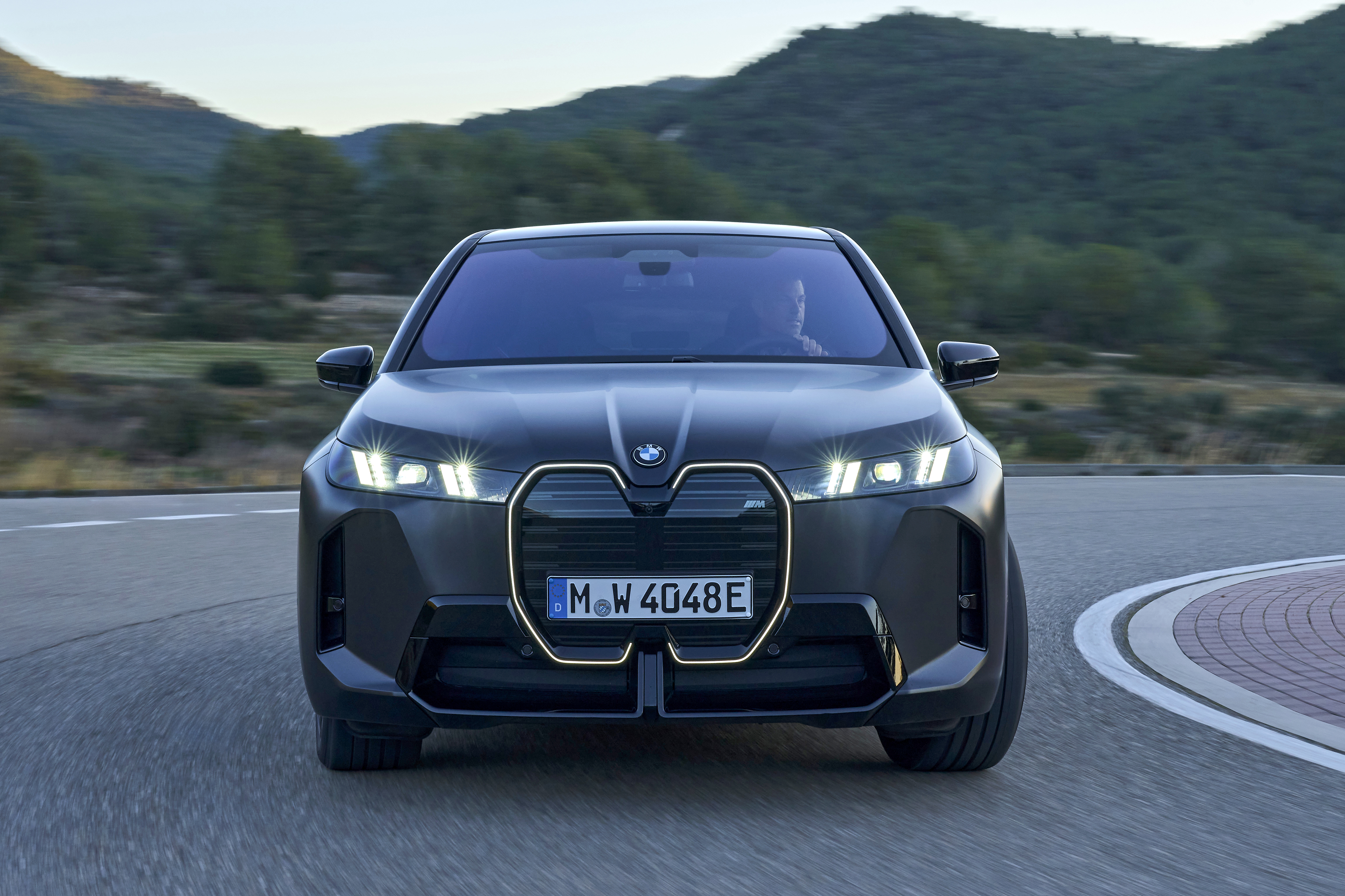 BMW iX electric SUV front view driving on a mountain pass