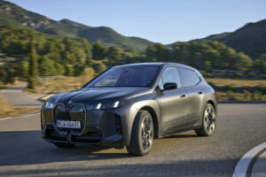Used BMW iX electric SUV in grey on a mountain road, front three-quarter view