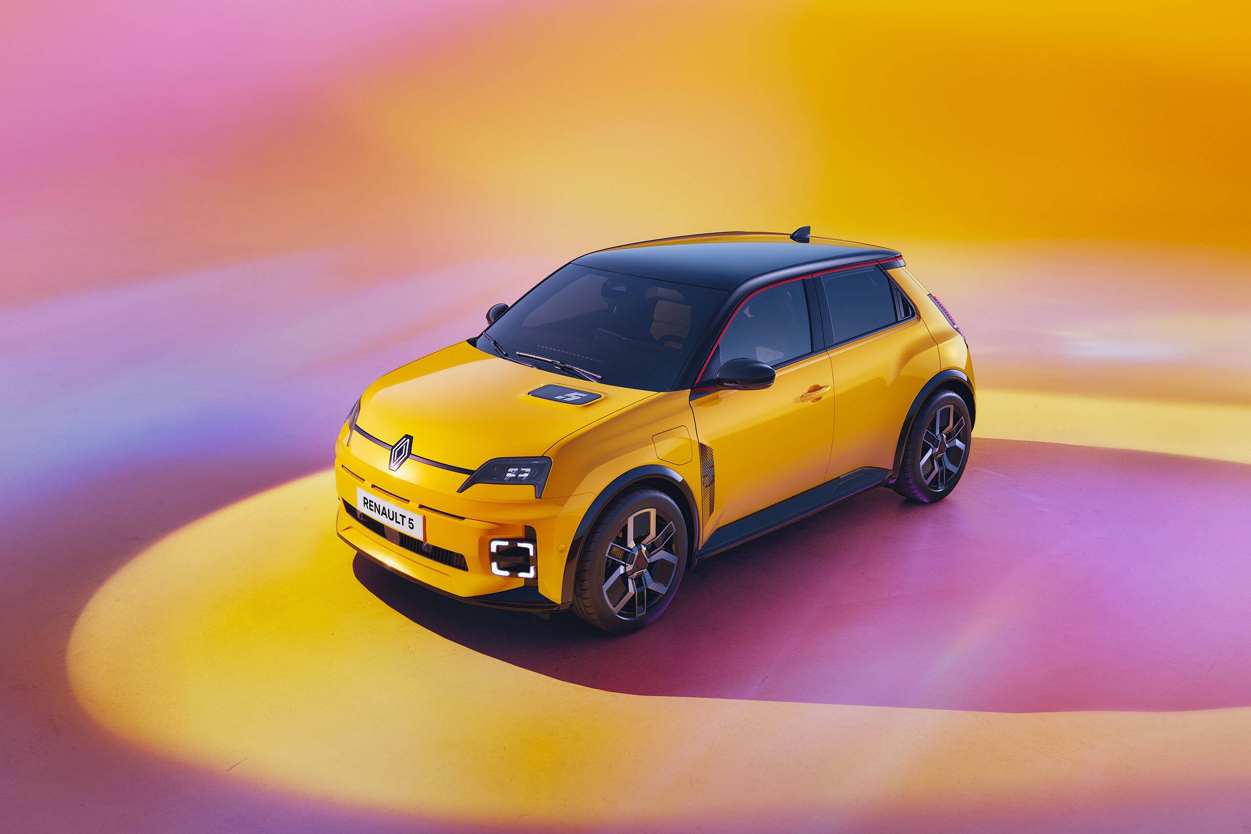 Renault 5 E-Tech in yellow, high-angle official studio image showing the front and side